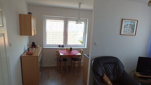 Un espai habitable reduït amb petita cuina, zona de menjador i una cadira de pell negra.