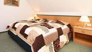 Un lit bien fait, recouvert d’une courtepointe, une table de chevet avec une lampe et un tableau accroché au mur.
