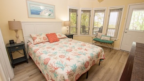 A bedroom with a bed, a nightstand, a lamp, a bench, and a door.