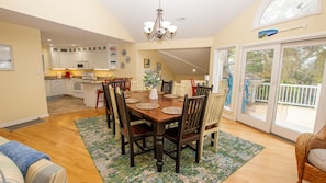 A spacious kitchen with white cabinets, a dining area with a wooden table and chairs, and a large sliding glass door leading to a backyard.
