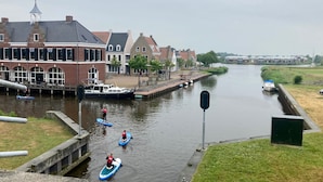 A canal with boats, a bridge, and buildings along the water. - Dike House Affordable 6-person Holiday Home Near the Sea Dike (Anjum)