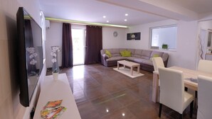 Una sala de estar moderna con un sofá, mesa de centro, televisor y un comedor con sillas.