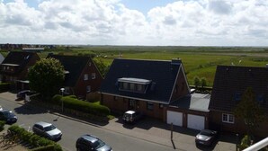 A residential area with houses, a parking lot, and a green field in the background. - Appartement 163 (Sylt)