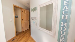 A hallway with a wooden door, a wall-mounted mirror, and a vertical sign reading "EACH HOUSE". - Oceanside, Hot Tub, Close to Beach, Sunroom, CP7, Shoulda Been Here Yesterday (Corolla)