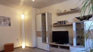Ein modernes Wohnzimmer mit Flachbildfernseher, integrierten Regalen und einem Schrank mit Glastüren.