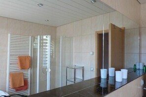 Une salle de bain moderne avec une douche à parois de verre, un meuble-lavabo avec un miroir et un porte-serviettes avec des serviettes.
