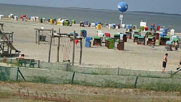 A beach with numerous colorful beach huts and a lifeguard tower. - Nordsee-ferienanlage -wohnung Langeoog- (Dornum)