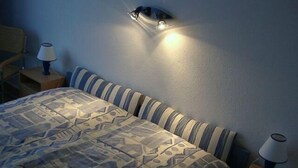 A bedroom with a patterned bedspread, striped pillows, and two bedside lamps. - Ferienwohnung im Wikingturm (Schleswig)