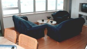 A room with two blue sofas, a small round table, and a television on a cabinet. - Ferienwohnung im Wikingturm (Schleswig)