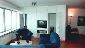 A living room with two blue sofas, a white cabinet, a television, and a lamp. - Ferienwohnung im Wikingturm (Schleswig)