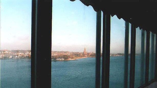 A view from a high-rise building overlooking a body of water with a distant landmark. - Ferienwohnung im Wikingturm (Schleswig)