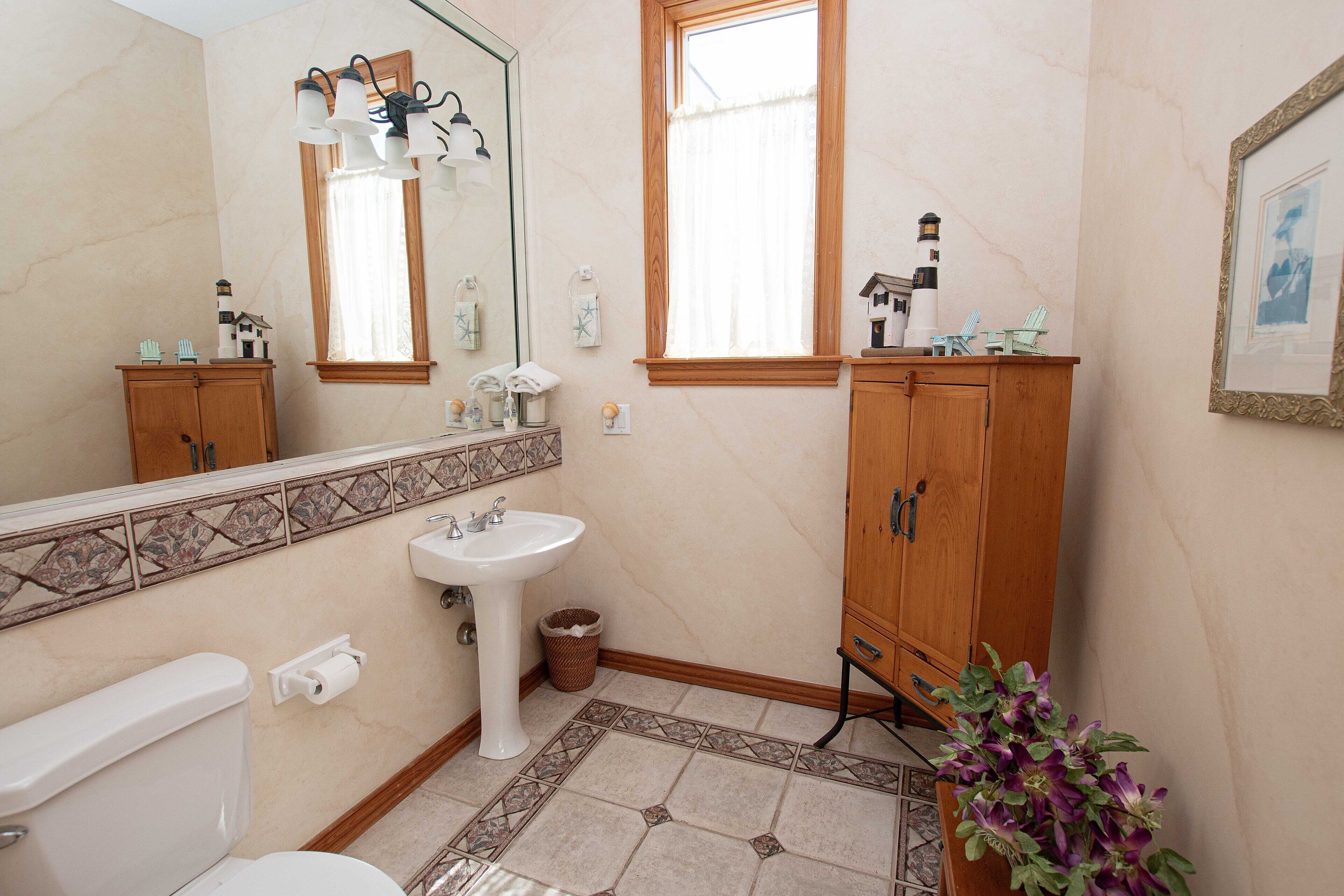 A bathroom with a toilet, sink, wooden cabinet, and a mirror.