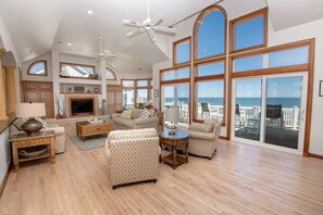 A spacious living room with a fireplace, multiple seating areas, and large windows offering ocean views. - OCEANFRONT, Private Pool, Ocean Views, Private Beach Access, PI250, Windrift (Corolla)