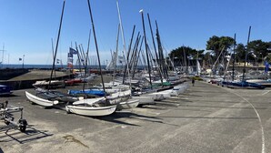 A marina with multiple sailboats docked in a concrete area, surrounded by trees and a clear blue sky. - PORT AN DRO - Studio in holiday rental in Carnac - UD98 (Carnac)