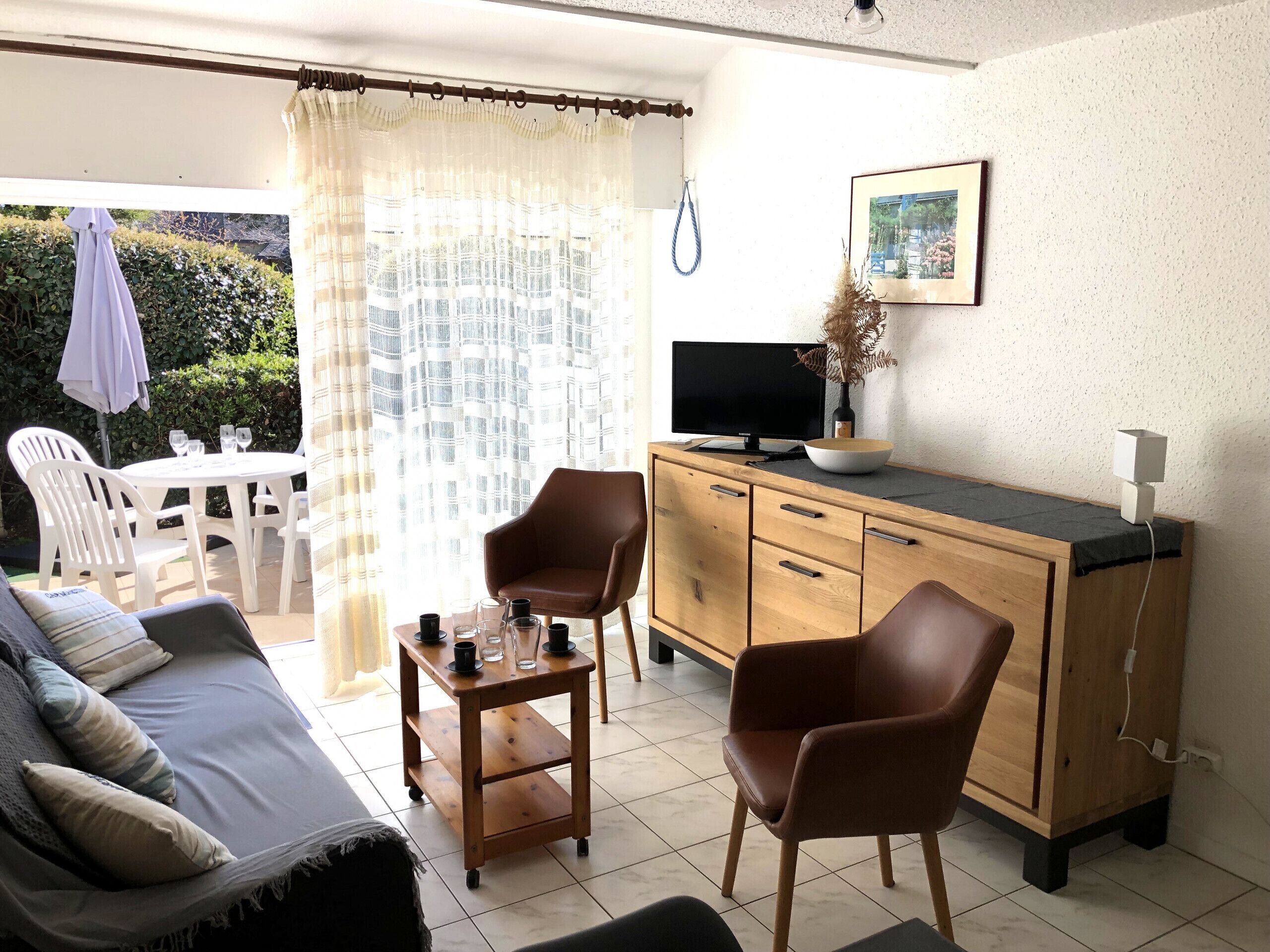Una sala de estar con un sofá, dos sillones, una mesita de centro, un televisor y un mueble aparador.