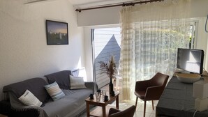 A living room with a sofa, two chairs, a small table, a TV, and a window with curtains. - PORT AN DRO - Studio in holiday rental in Carnac - UD98 (Carnac)