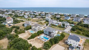 Vista aérea de una zona residencial costera con casas, una piscina y una playa.