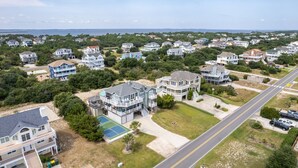 Zona residencial con casas, una carretera y una playa al fondo.