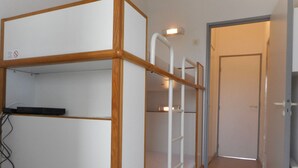 A narrow hallway with bunk beds and a door at the end.