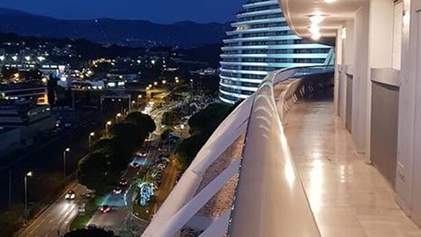 A modern hotel with a curved balcony overlooking a cityscape at night.