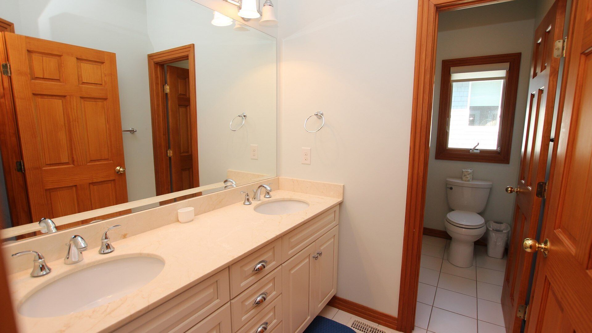 A bathroom with two sinks, a large mirror, and wooden doors.