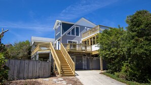 A two-story house with a wooden deck and a staircase leading to the upper level. - Oceanside, Private Pool, Screened Porch, Hot Tub! WW910, Serenity on the Beach (Corolla)