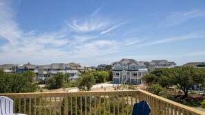 A residential area with multiple two-story houses, a wooden deck, and a clear blue sky. - Oceanside, Private Pool, Screened Porch, Hot Tub! WW910, Serenity on the Beach (Corolla)