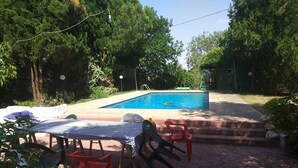 A pool area with a checkered table and plastic chairs, surrounded by trees and a clear blue sky. - Quinta La Alpujarra (Batres)