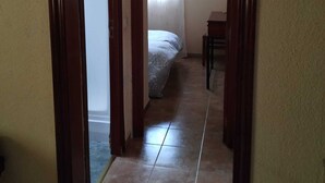 A narrow hallway with a bed and a chair in the background. - Quinta La Alpujarra (Batres)