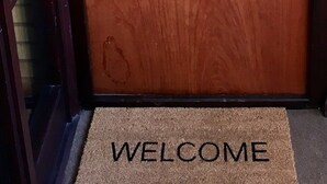A wooden door with a metal lock and a doormat with "WELCOME" written on it.