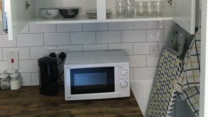 A kitchen with white cabinets, a microwave, and a coffee maker.