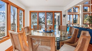 A spacious dining area with a glass table surrounded by wicker chairs, large windows, and a view of the outdoors. - Soundfront, Amazing Sound Views! Sunsets, Yard, Hot Tub, MS100, Timberly II (Corolla)