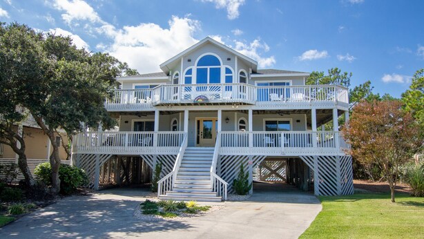 A two-story house with a balcony, a front porch, and a staircase leading to the entrance.