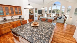 A spacious kitchen with granite countertops, wooden cabinets, and a dining area with a large island.