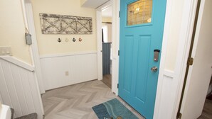 A hallway with a blue door, a decorative wall piece, and a herringbone floor pattern. - Walk to Beach, Lighthouse & Historic Corolla, Near Corolla Adventure Park, Pool & Hot Tub (Corolla)
