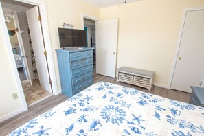 A bedroom with a bed, a dresser, a bench, and a door.