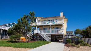 A two-story beachfront house with a balcony, a covered outdoor area, and a sandy driveway. - Walk to Beach, Lighthouse & Historic Corolla, Near Corolla Adventure Park, Pool & Hot Tub (Corolla)