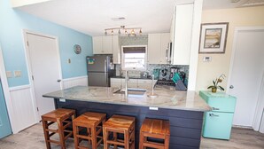 A kitchen with a central island, bar stools, a refrigerator, and a vintage-style icebox. - Walk to Beach, Lighthouse & Historic Corolla, Near Corolla Adventure Park, Pool & Hot Tub (Corolla)