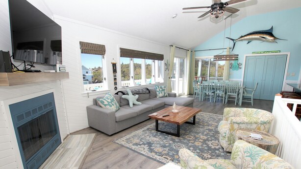 A living room with a fireplace, sofa, coffee table, and patterned chairs. - Walk to Beach, Lighthouse & Historic Corolla, Near Corolla Adventure Park, Pool & Hot Tub (Corolla)