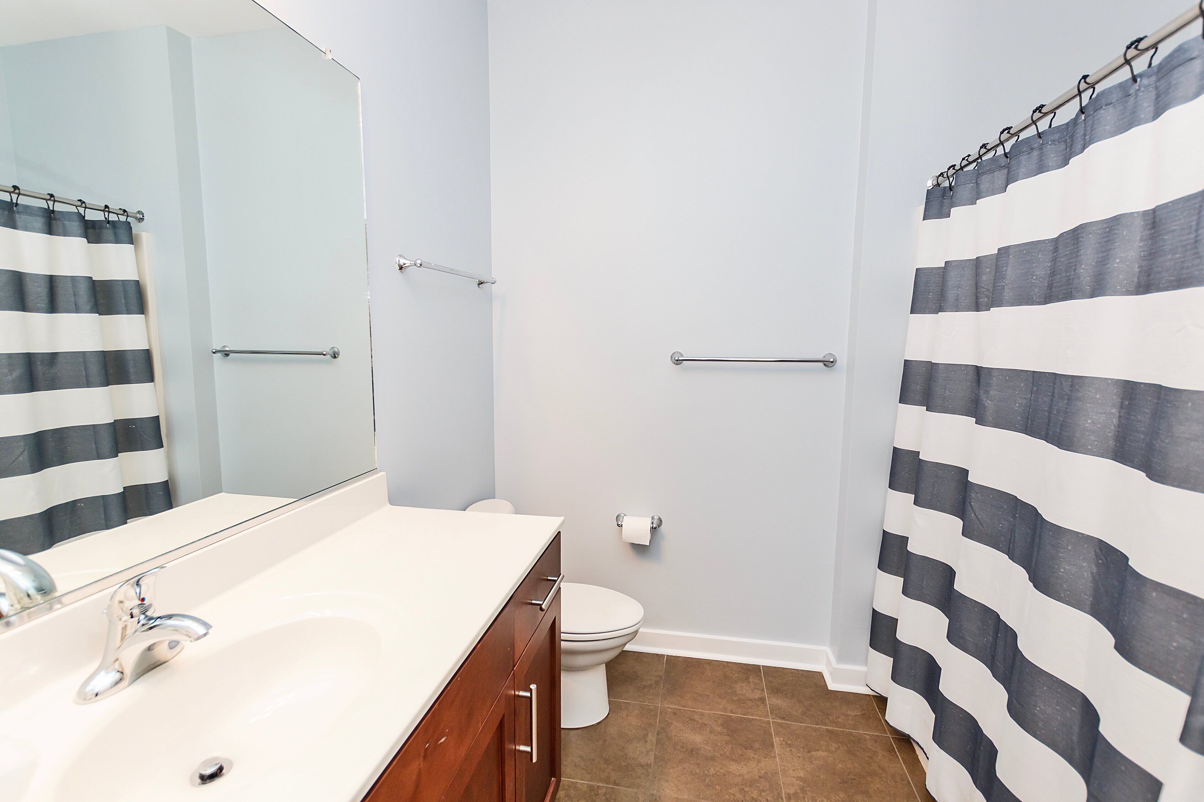 A bathroom with a white sink, a mirror, a toilet, and a shower curtain.