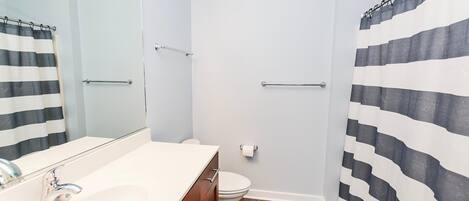 A bathroom with a white sink, a mirror, a toilet, and a shower curtain.