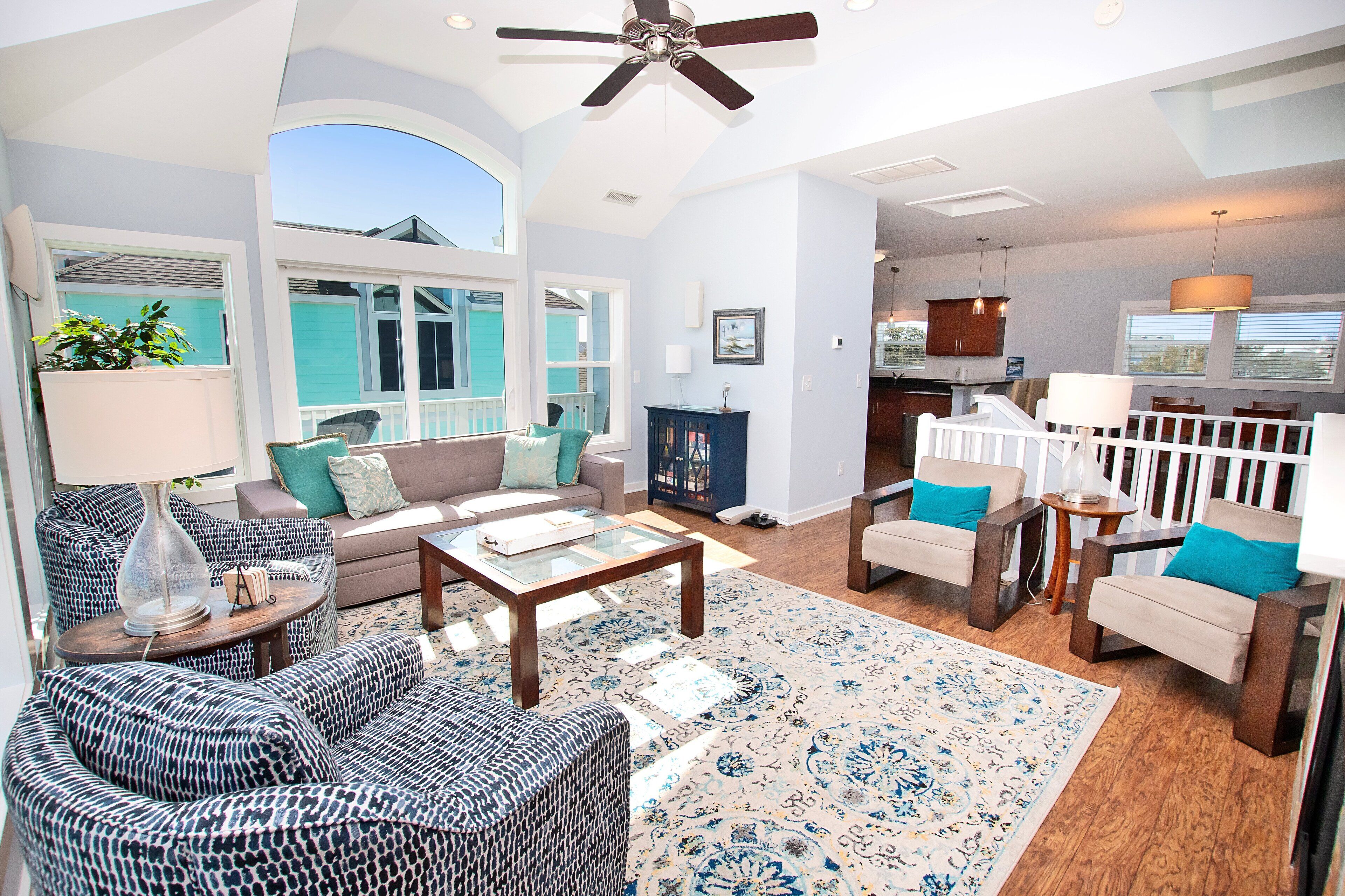 A spacious living room with a large window, a ceiling fan, and a fireplace.
