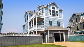 A multi-story residential building with a front garage, a covered entryway, and a fenced yard. - Moms Dream- Oceanside, Comm Pool, Hot Tub, Yard, CB10, Dads Mercedes (Corolla)