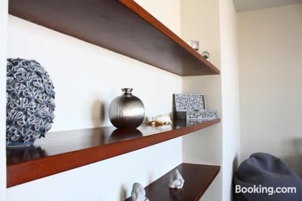 Simple, functional space with a wooden shelf unit and a variety of decorative items.