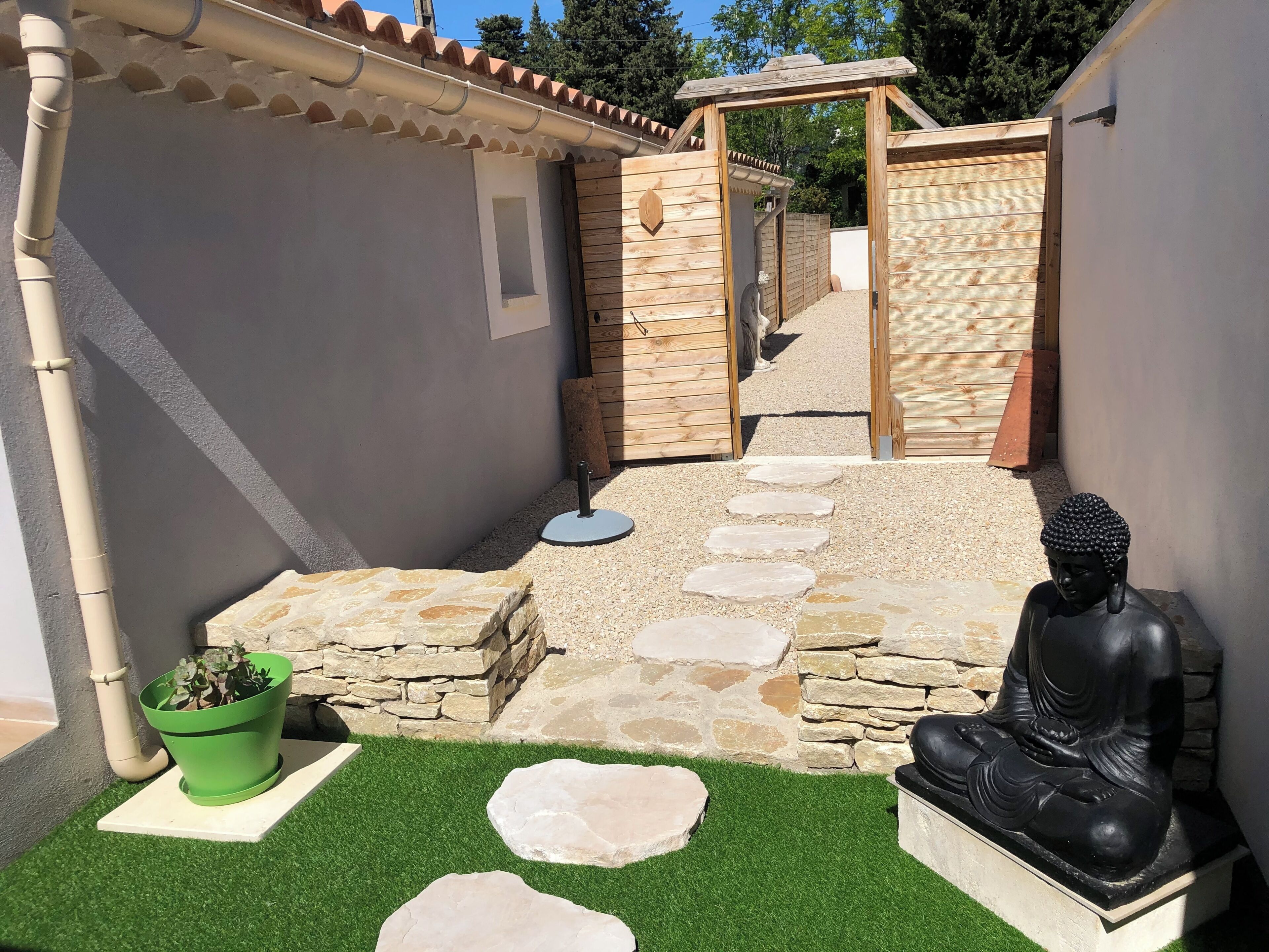 Une cour avec une statue de Bouddha, des marches en pierre et une plante verte.