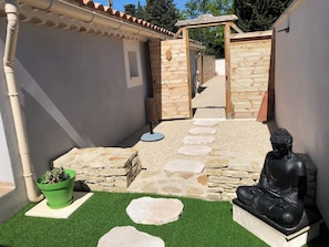 A courtyard with a Buddha statue, stone steps, and a green plant. - Le Zen: an air-conditioned house with a pool and a private pool house. (L'Isle-sur-la-Sorgue)