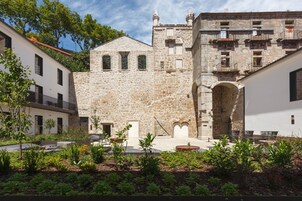 Une cour bordée de bâtiments en pierre, avec une arche centrale et des espaces de repos en plein air.