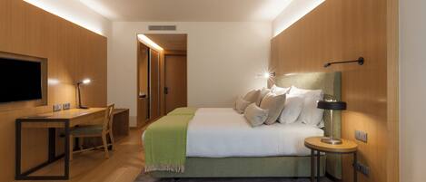 A modern bedroom with a bed, bedside table, lamp, and a desk with a chair.