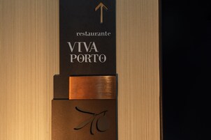 Placa do restaurante 'VIVA PORTO' com design minimalista, exibindo uma seta indicativa e texto estilizado.