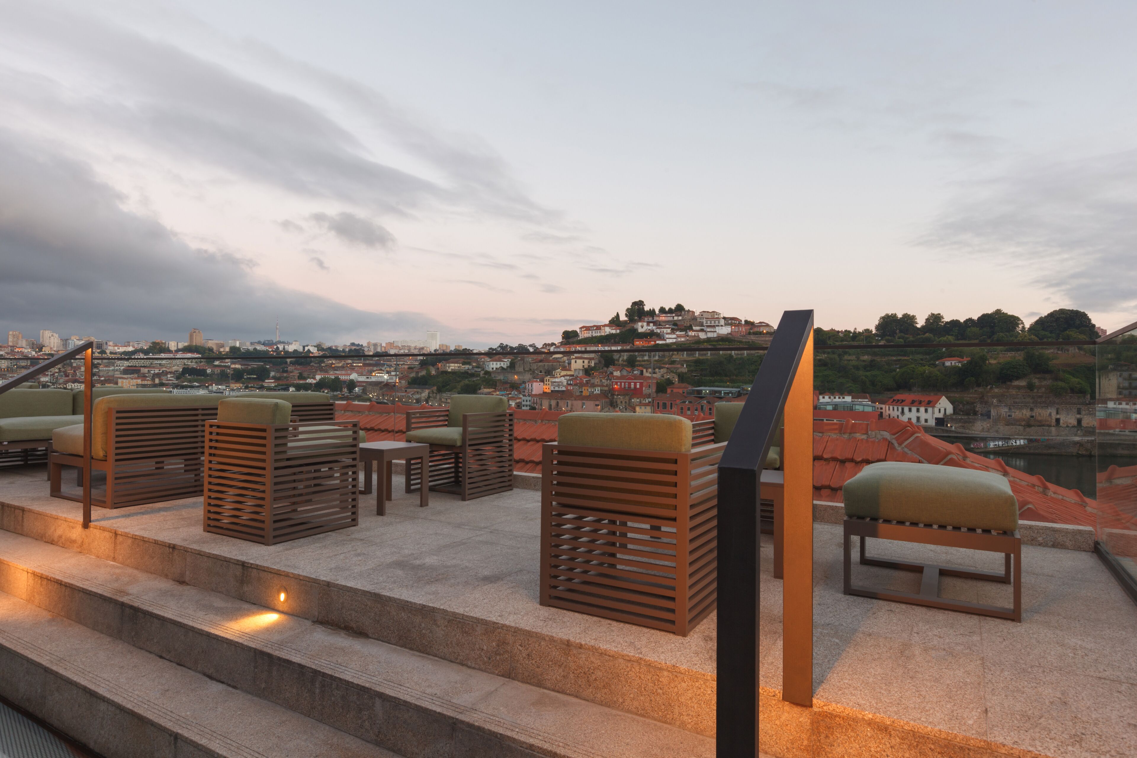 Outdoor seating with steps leading up to a terrace overlooking a cityscape.